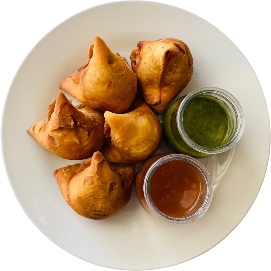 A plate of hot samosas with green chutney and tamarind chutney
